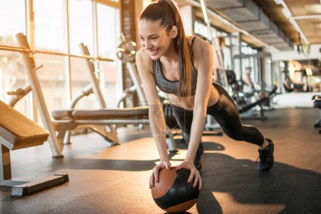 Téléchargez les photos : Belle femme sportive faisant pousser sur la balle dans la salle de gym - en image libre de droit