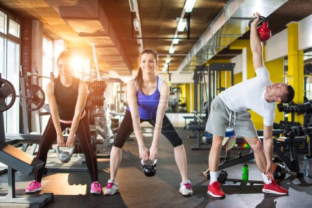 Photo for Group of sporty people doing exercises with kettlebells in gym - Royalty Free Image