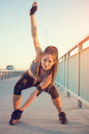 Photo for Beautiful sporty girl warming up before morning workout - Royalty Free Image