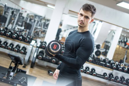 Photo for Portrait of young handsome man lifting weights in the gym - Royalty Free Image