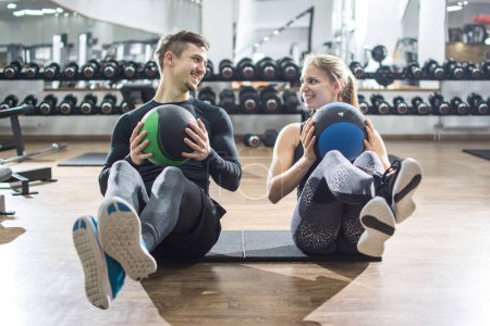 Foto de Ajuste pareja haciendo ejercicio abdominal con bolas de fitness en el gimnasio - Imagen libre de derechos