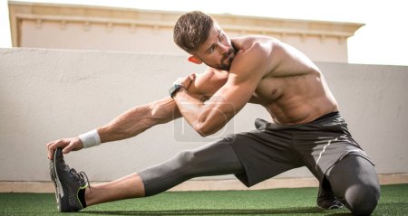 Foto de Deportista musculoso sin camisa calentándose antes del entrenamiento deportivo en el gimnasio - Imagen libre de derechos