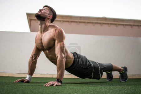 Hombre guapo relajado haciendo ejercicio de yoga en cobra posan al aire libre