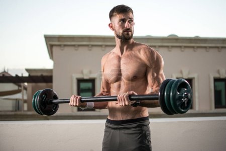 Téléchargez les photos : Homme musclé avec abdos, épaules, biceps, triceps et entraînement thoracique parfaits avec haltère à la salle de gym extérieure - en image libre de droit