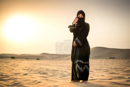 Photo for Full length portrait of Arab woman in burka clothing standing in the desert - Royalty Free Image
