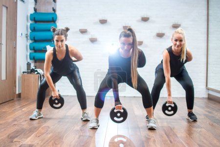 Photo for Group of three young sporty women exercising with weights at gym - Royalty Free Image