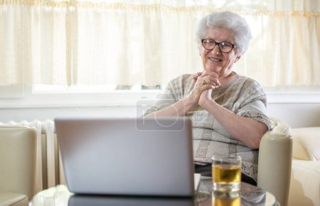Foto de Feliz mujer mayor que tiene videollamada en el ordenador portátil en casa - Imagen libre de derechos