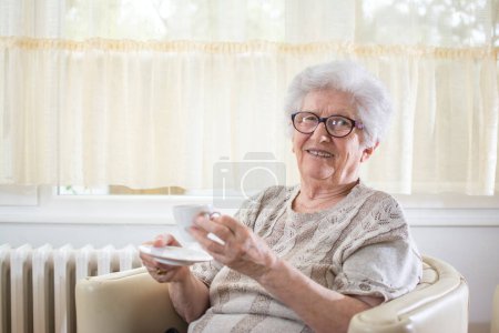 Foto de Sonriente mujer mayor bebiendo café en casa - Imagen libre de derechos