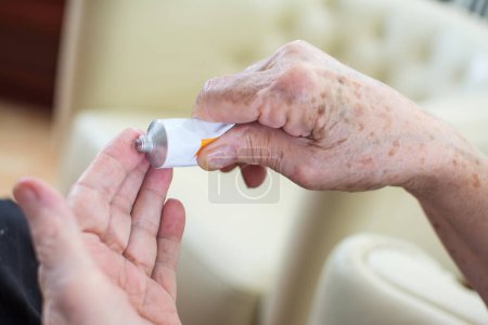 Photo for Close up of wrinkled hands applying cream at home - Royalty Free Image