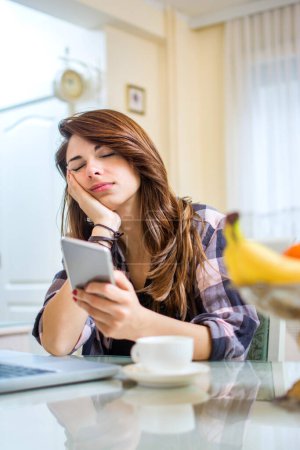Téléchargez les photos : Portrait de jeune femme fatiguée et endormie tenant un téléphone portable - en image libre de droit