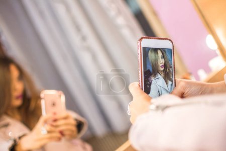 Téléchargez les photos : Une jeune femme se prépare pour une soirée. Fille prendre un selfie sur le téléphone intelligent pour le réseau social avant d'aller à la fête - en image libre de droit