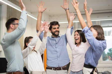 Photo for Team of business people with their hands up celebrating successful completed task in office - Royalty Free Image