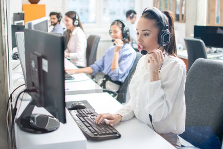 Photo for Beautiful female customer service executive talking with a customer using headset at call center - Royalty Free Image