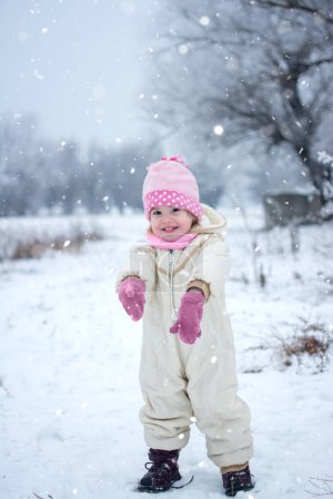 Foto de Retrato de larga duración de una linda niña divirtiéndose y jugando en el día de invierno nevado - Imagen libre de derechos