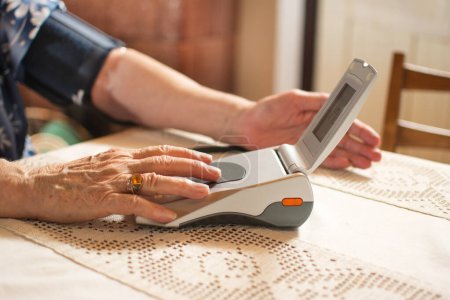 Téléchargez les photos : Femme âgée mesurant sa tension artérielle - en image libre de droit