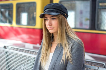Foto de Retrato de cerca de una hermosa joven con sombrero esperando el tren en la estación de tren - Imagen libre de derechos