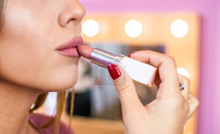Téléchargez les photos : Gros plan de la jeune femme attrayante appliquant rouge à lèvres - en image libre de droit