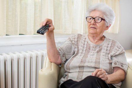 Téléchargez les photos : Femme âgée Regarder la télévision à la maison - en image libre de droit