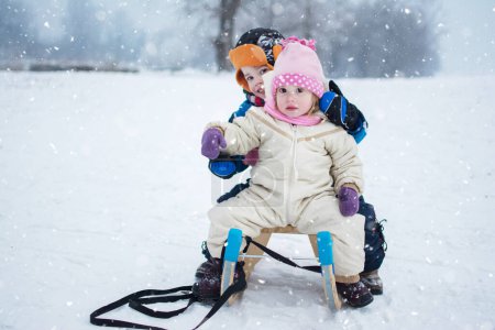 Téléchargez les photos : Petite fille et garçon assis sur un traîneau. Enfants profitant d'une promenade en traîneau en hiver - en image libre de droit