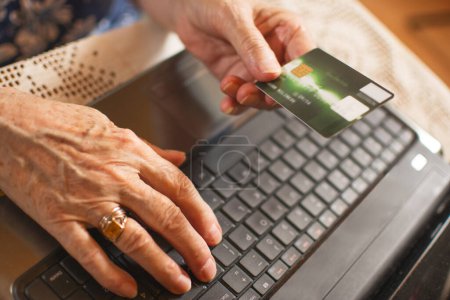 Photo for Close up of senior womans hands with laptop computer and credit card - Royalty Free Image