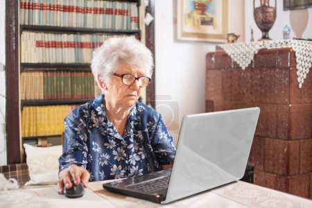 Old woman working on laptop computer at home