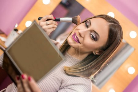 Téléchargez les photos : Belle femme appliquant le maquillage à la maison - en image libre de droit