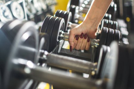 Photo for Close up of womans hand holding dumbbell in gym - Royalty Free Image