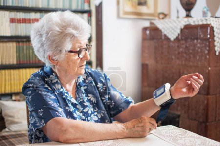 Foto de Mujer mayor midiendo su presión arterial en casa - Imagen libre de derechos