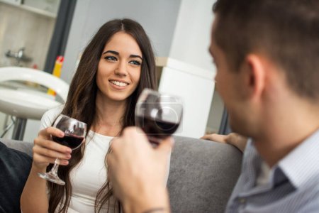 Téléchargez les photos : Jeune femme buvant du vin rouge avec son petit ami à la maison - en image libre de droit