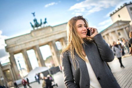 Foto de Hermosa mujer joven en ropa casual inteligente hablando en el teléfono móvil al aire libre - Imagen libre de derechos