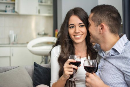 Foto de Feliz joven pareja bebiendo vino en casa - Imagen libre de derechos