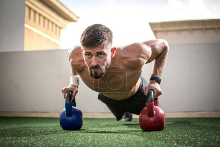Photo for Portrait of a muscular man doing push ups with kettle bells in gym - Royalty Free Image