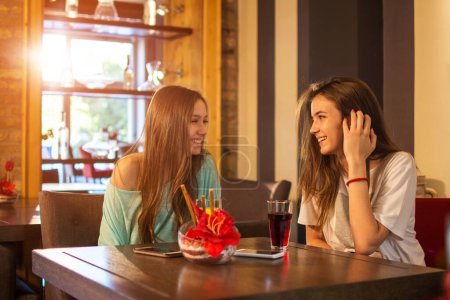 Téléchargez les photos : Deux adolescentes parlent dans un café - en image libre de droit