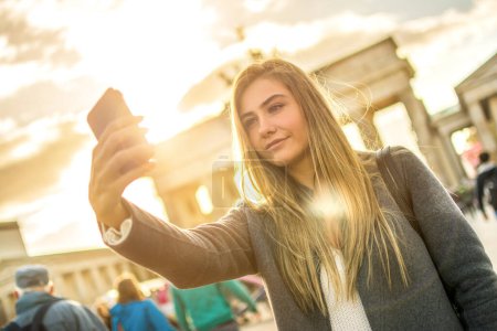 Foto de Mujer joven con smartphone tomando autorretrato mientras posa en el centro de Berlín, Alemania - Imagen libre de derechos