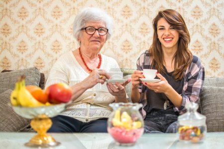 Abuela disfrutando de la taza de café con su nieta en casa