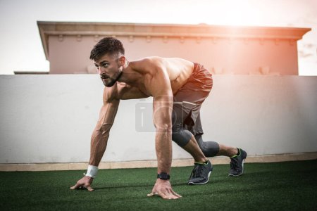 Foto de Un joven musculoso sin camisa entrenando antes de correr al aire libre. Calentamiento antes de un entrenamiento - Imagen libre de derechos