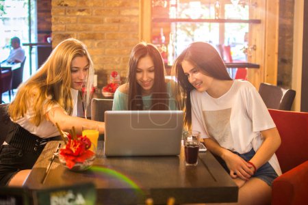 Photo for Teen girls using laptop together in cafe - Royalty Free Image