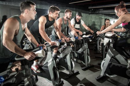 Foto de Grupo de deportistas haciendo ejercicio en bicicletas de spinning en el gimnasio - Imagen libre de derechos
