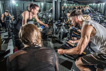 Photo for Group of young people having cycling class with their female instructor at gym - Royalty Free Image