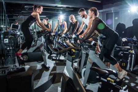 Photo for Group of sporty people training on exercise bikes together at gym - Royalty Free Image