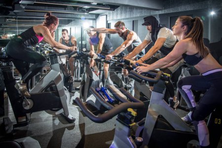 Téléchargez les photos : Excitation sportifs travaillant sur le cours de cyclisme à la salle de gym - en image libre de droit
