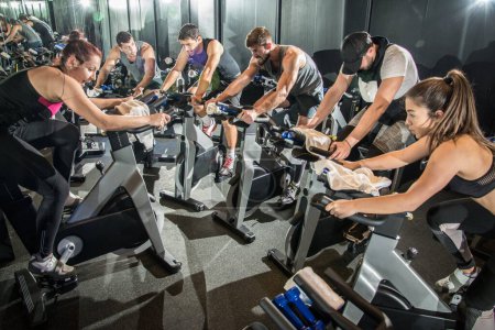 Photo for Group of fit people working out on spinning class in gym - Royalty Free Image