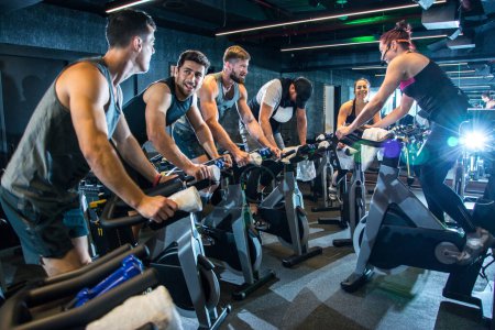 Photo for Group of happy sporty people riding spinning bikes together in gym - Royalty Free Image
