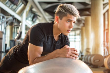 Photo for Handsome young man doing plank exercise on fitness ball at gym. Blonde muscular man doing plank on pilates ball - Royalty Free Image