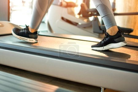 Photo for Legs of woman running on a treadmill in gym, close-up - Royalty Free Image