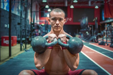 Téléchargez les photos : Portrait d'un homme en forme torse nu faisant des squats avec des poids pendant un entraînement de renforcement à la salle de gym - en image libre de droit