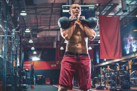 Photo for Young shirtless sportsman performing exercises with a kettle bell at gym - Royalty Free Image