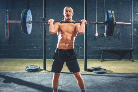 Photo for Fit shirtless sportsman lifting heavy barbells in the gym - Royalty Free Image