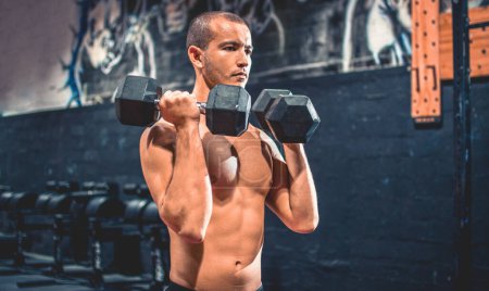 Photo for Portrait of young sportsman working out with weights at gym - Royalty Free Image