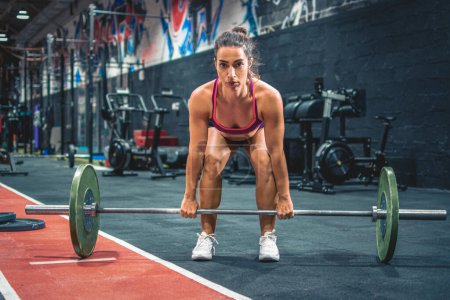 Photo for Young fitness women doing deadlift exercise with heavy weight bar in the gym - Royalty Free Image